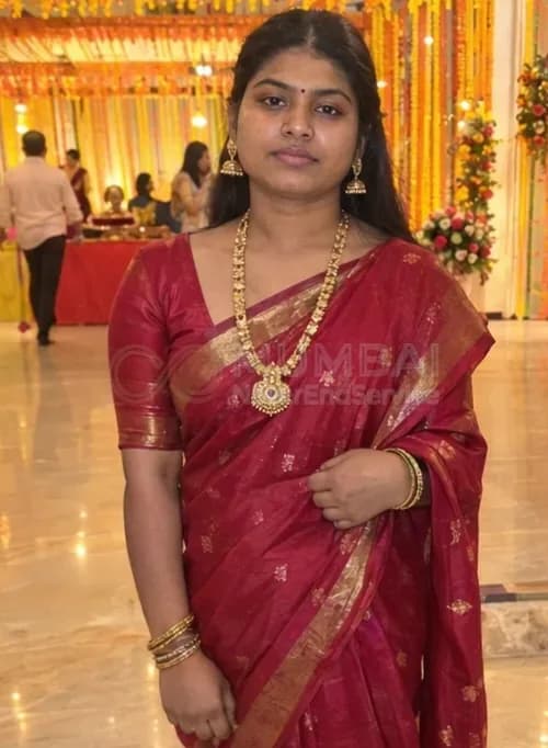 Desi escort in a red silk saree and gold jewellery at a Mumbai wedding hall