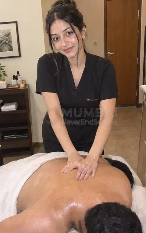 Massage girl in a black spa tunic giving a man an oil back massage in Mumbai