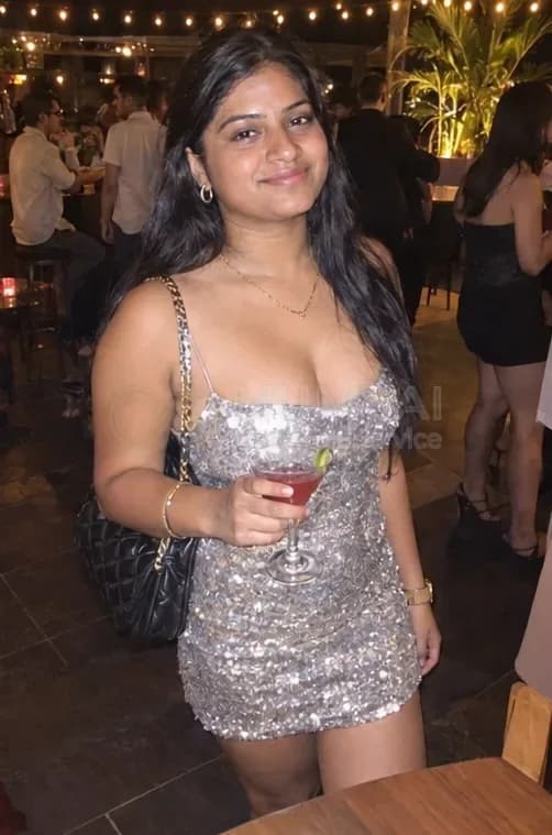 Mumbai escort in a silver sequin dress holding a cocktail at a rooftop party